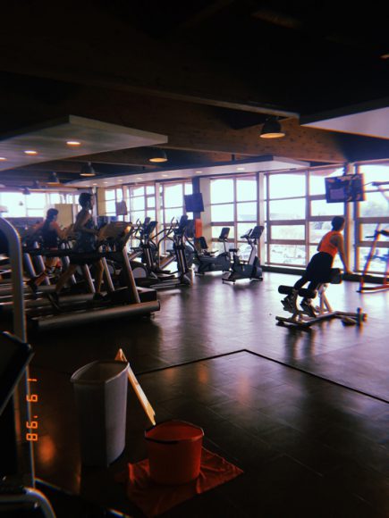 Personas haciendo ejercicio en el gym, junto con los útiles de aseo.